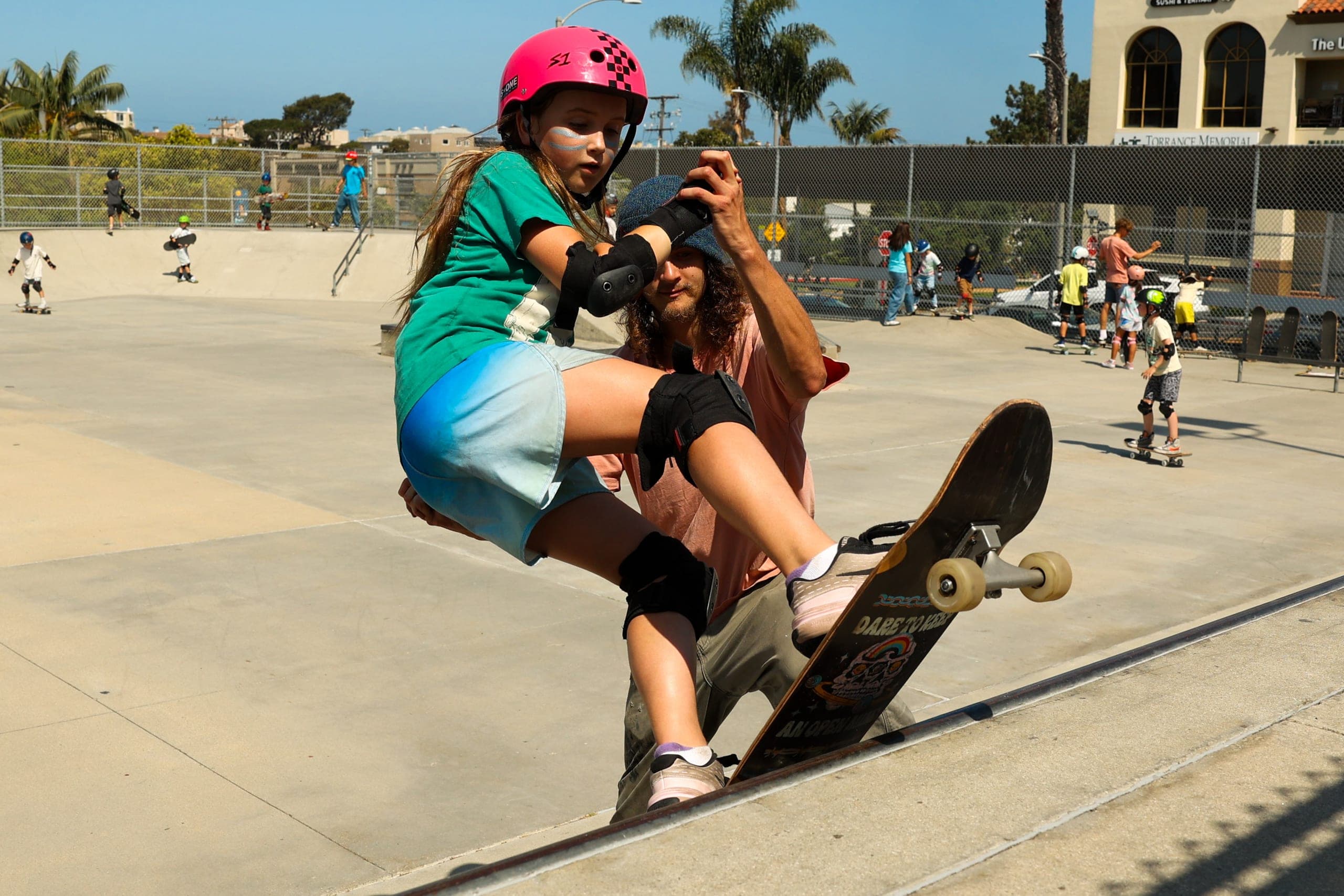 A coach spotting a skater dropping in at the Hermosa Beach Skatepark