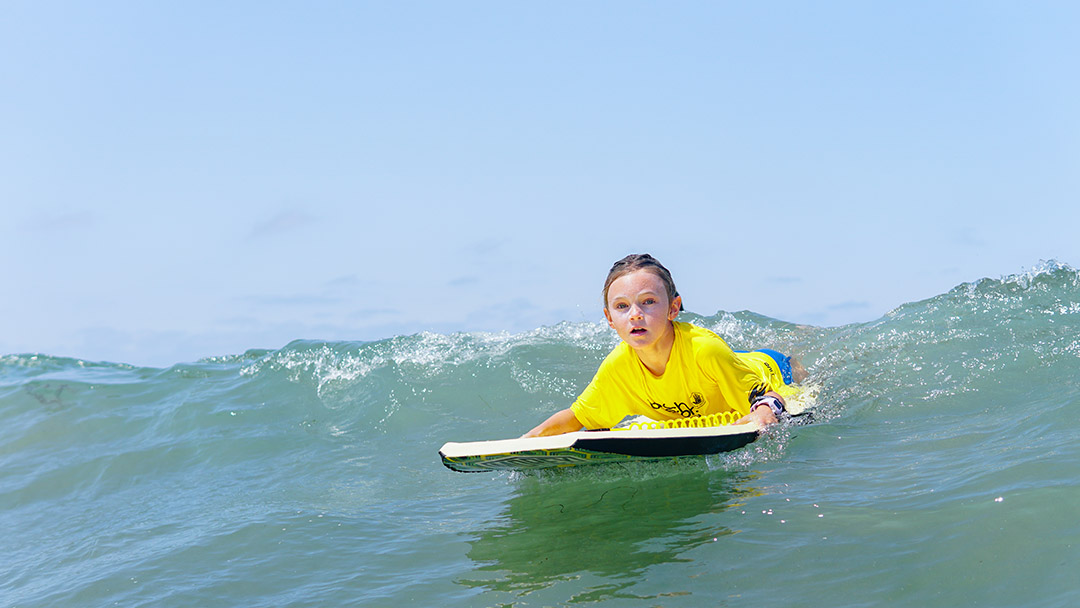 A girl has fun boogey boarding at Beach Sports kids summer camp in Redondo Beach