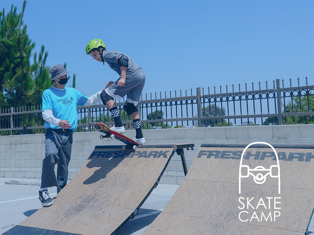 An instructor teaching a child how to skateboard at skate camp in Manhattan Beach