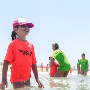A group of kids and counselors in the shoreline at Manhattan Beach Beach Sports minnows kids summer beach camp. Smiling