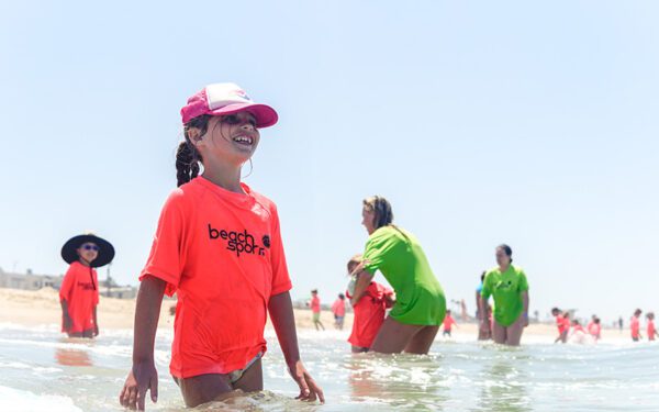 A group of kids and counselors in the shoreline at Manhattan Beach Beach Sports minnows kids summer beach camp. Smiling