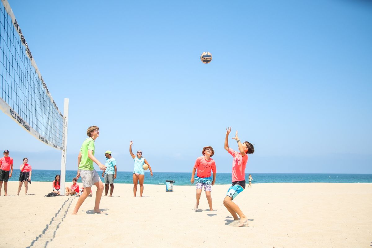 A beachsports Camp counselor with a safety flotation device with kids at summer camp at the Ocean shore