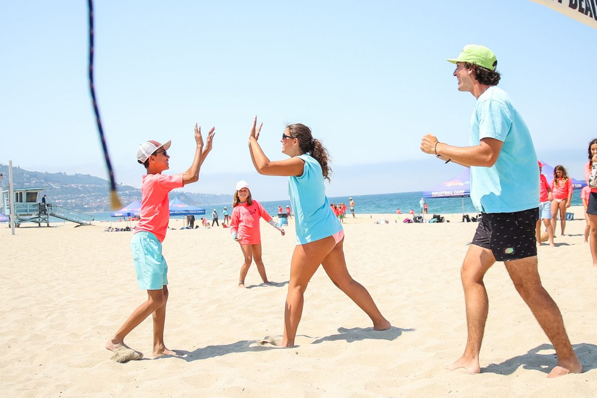 Beach camp counselor and child camper with safety floating device  instructs a child on ocean safety at the shore