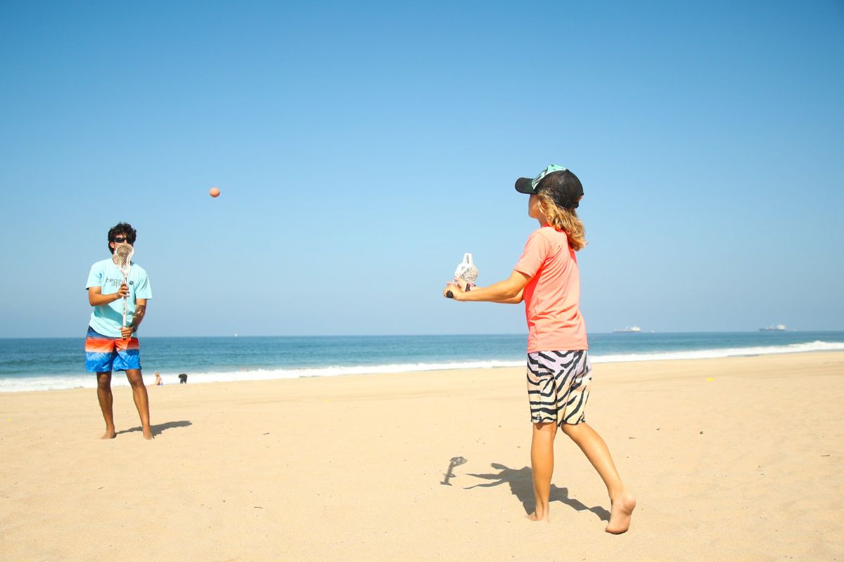 Kids pointing on the beach at summer beach camp with a camp counselor 