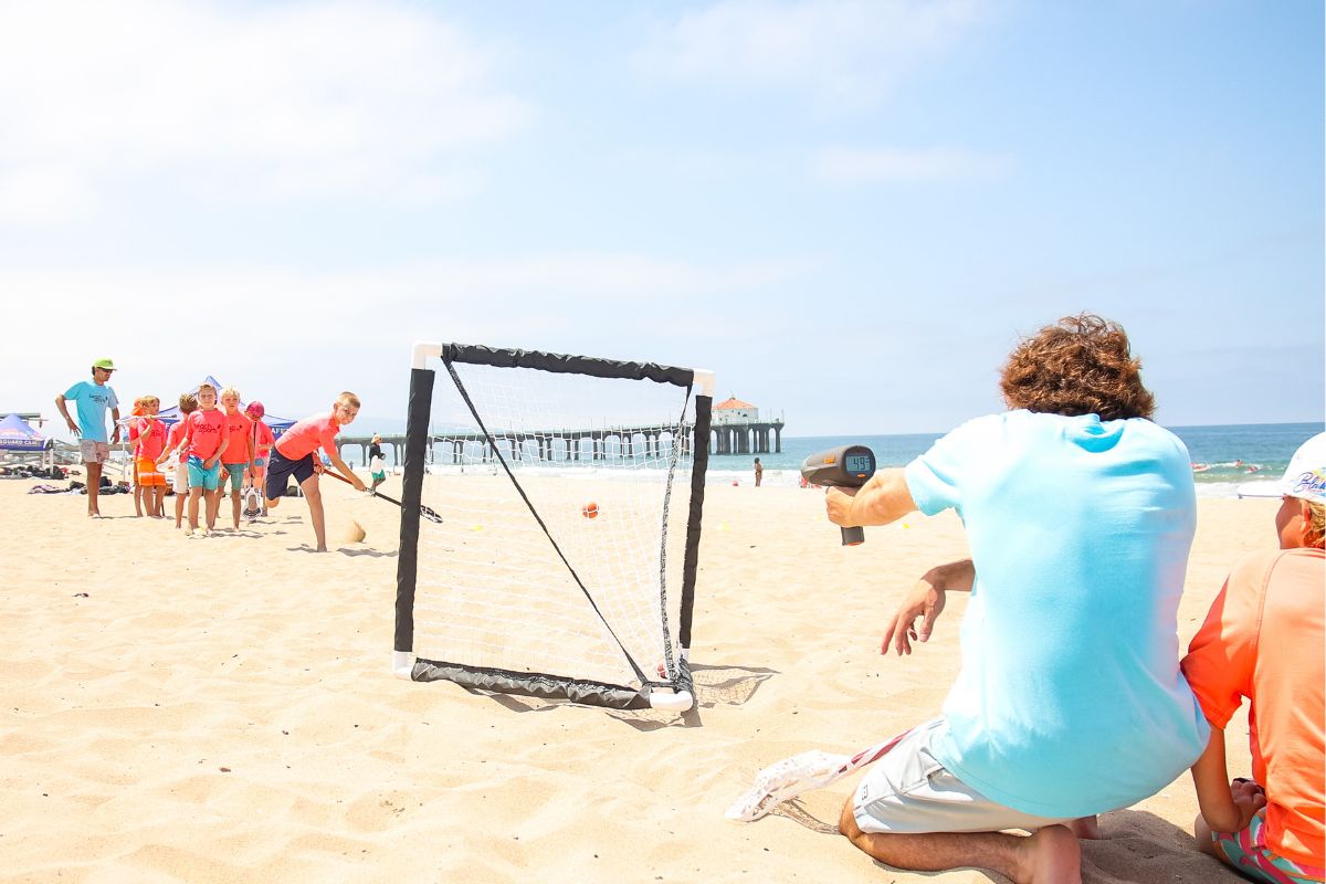 Small children on the beach at beach Camp in the summertime with a camp counselor pointing at something