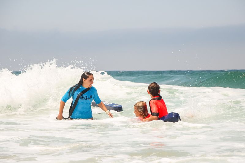 A beachsports Camp counselor with a safety flotation device with kids at summer camp at the Ocean shore