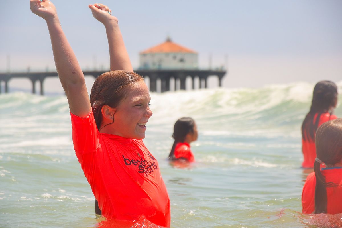 Beach camp counselor and child camper with safety floating device  instructs a child on ocean safety at the shore