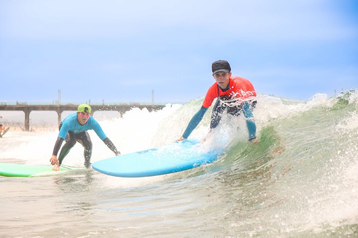 Beach camp counselor and child camper with safety floating device  instructs a child on ocean safety at the shore