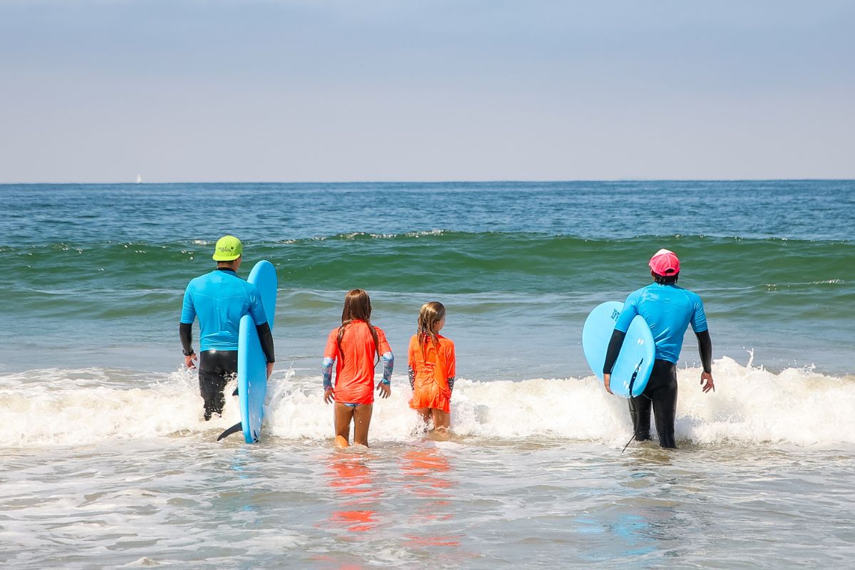 Kids pointing on the beach at summer beach camp with a camp counselor 