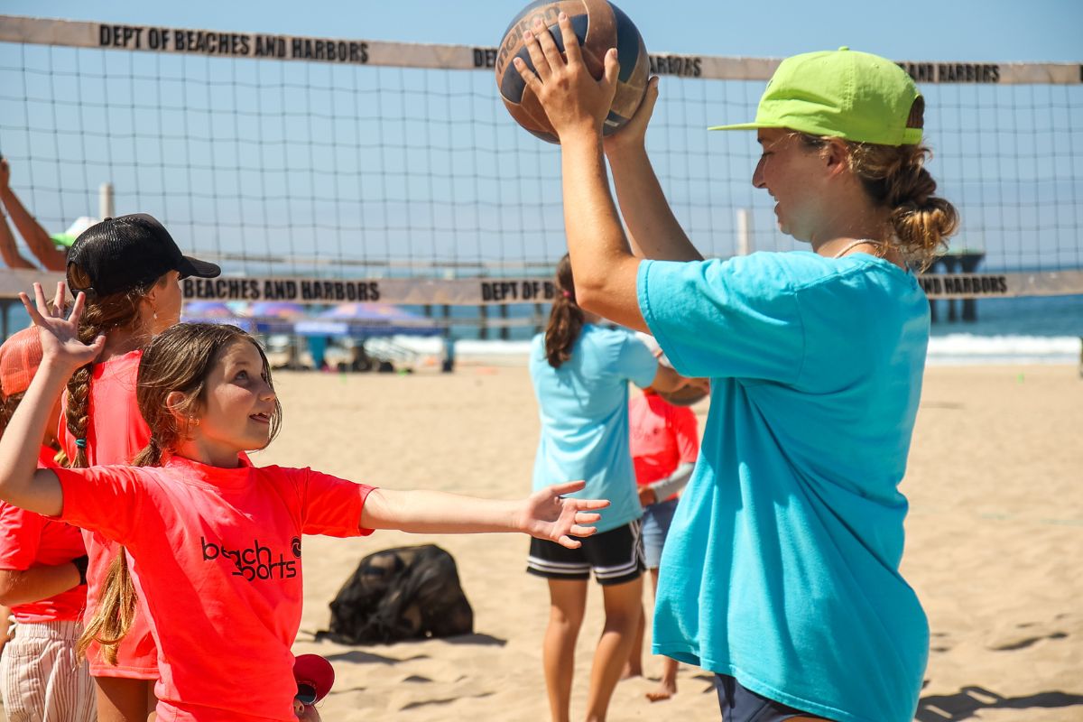 Kids pointing on the beach at summer beach camp with a camp counselor 