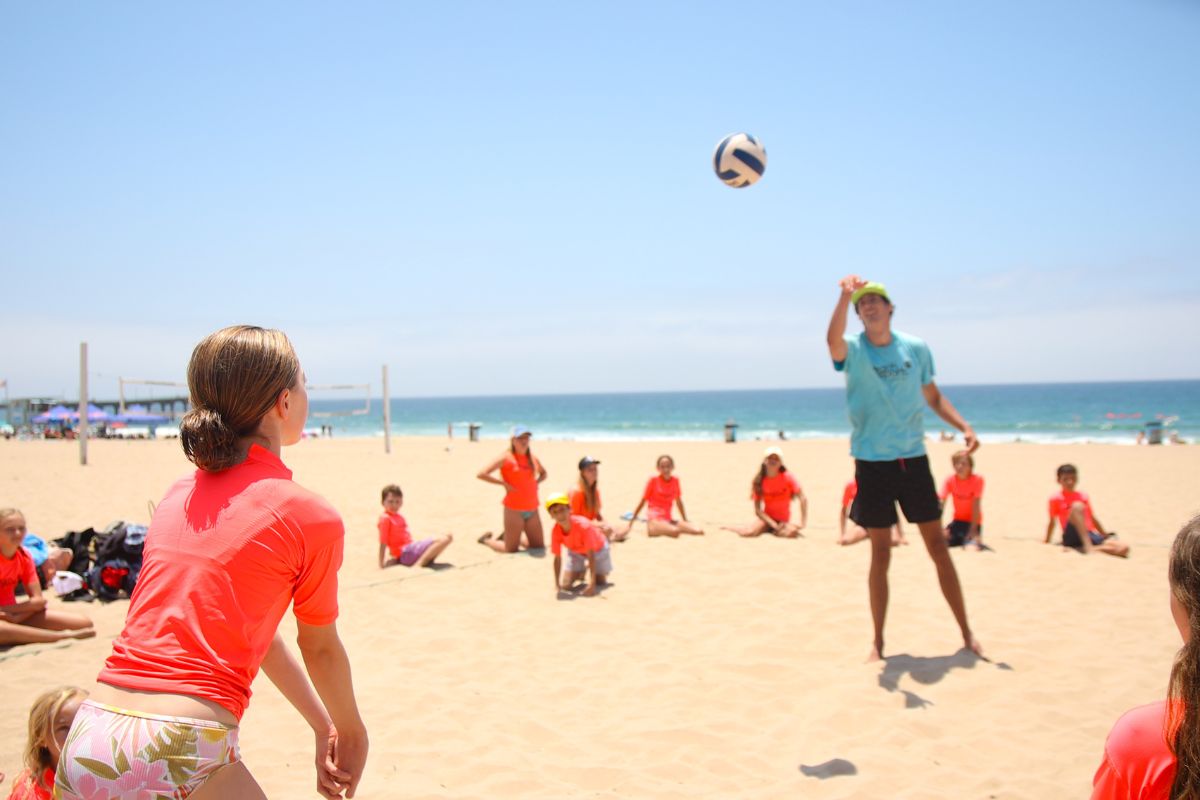 Small children on the beach at beach Camp in the summertime with a camp counselor pointing at something